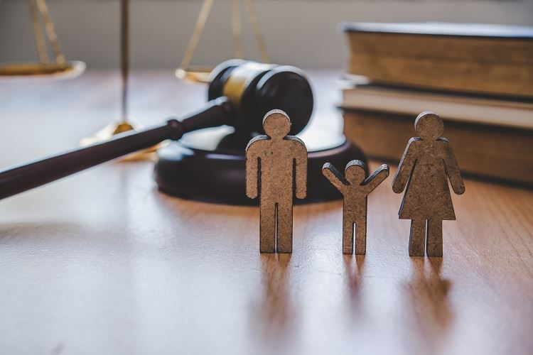 Two adult and one child shaped wooden figurines on a law desk.